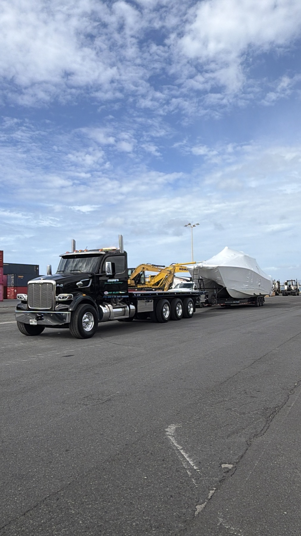 Stone's truck hauling a boat and excavator near Honolulu harbor
