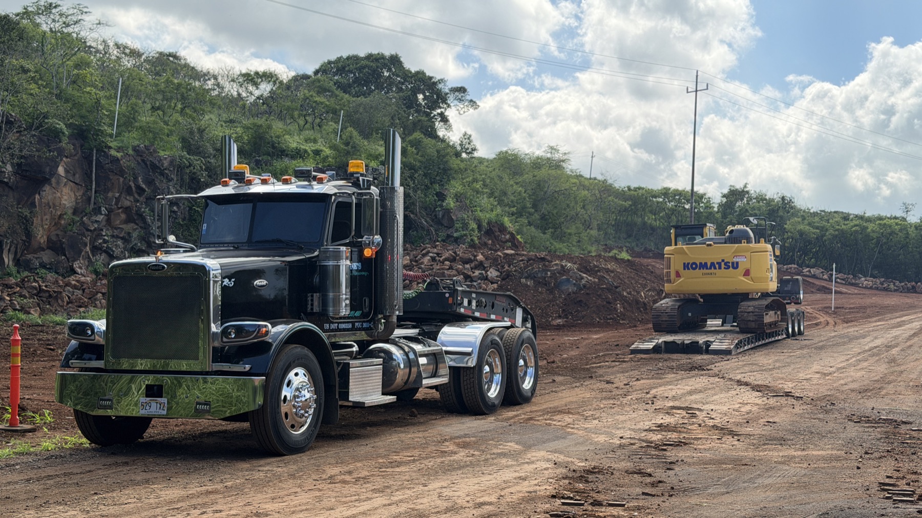 Stone's lowboy hauling a Komatsu excavator along a quarry road