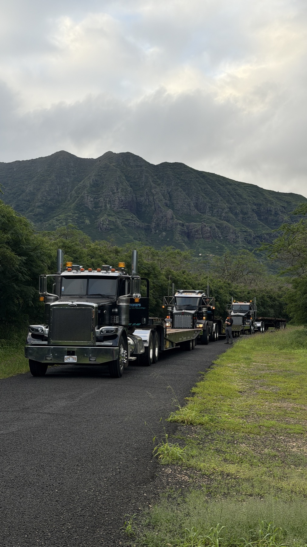 Stone's trucks in convoy with Oahu's green mountains behind them
