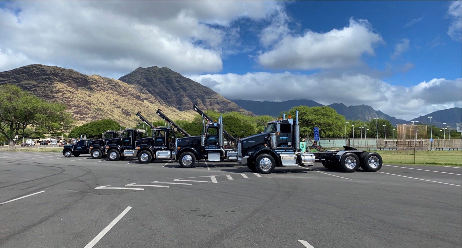 Stone's truck hauling a loaded dumpster bin through Honolulu at dusk