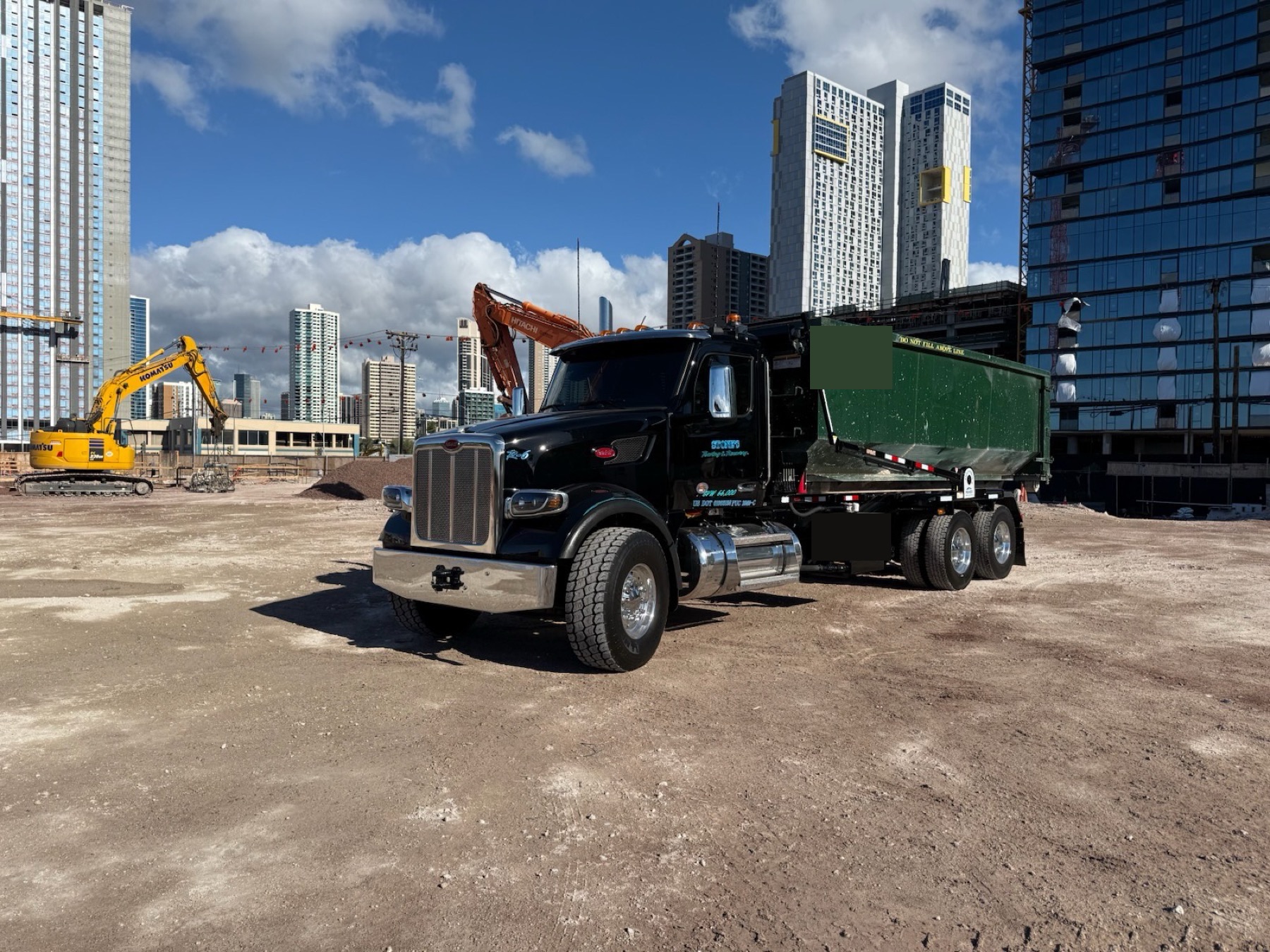 Stone's truck hauling a scrap metal recycling bin in front of the Honolulu skyline